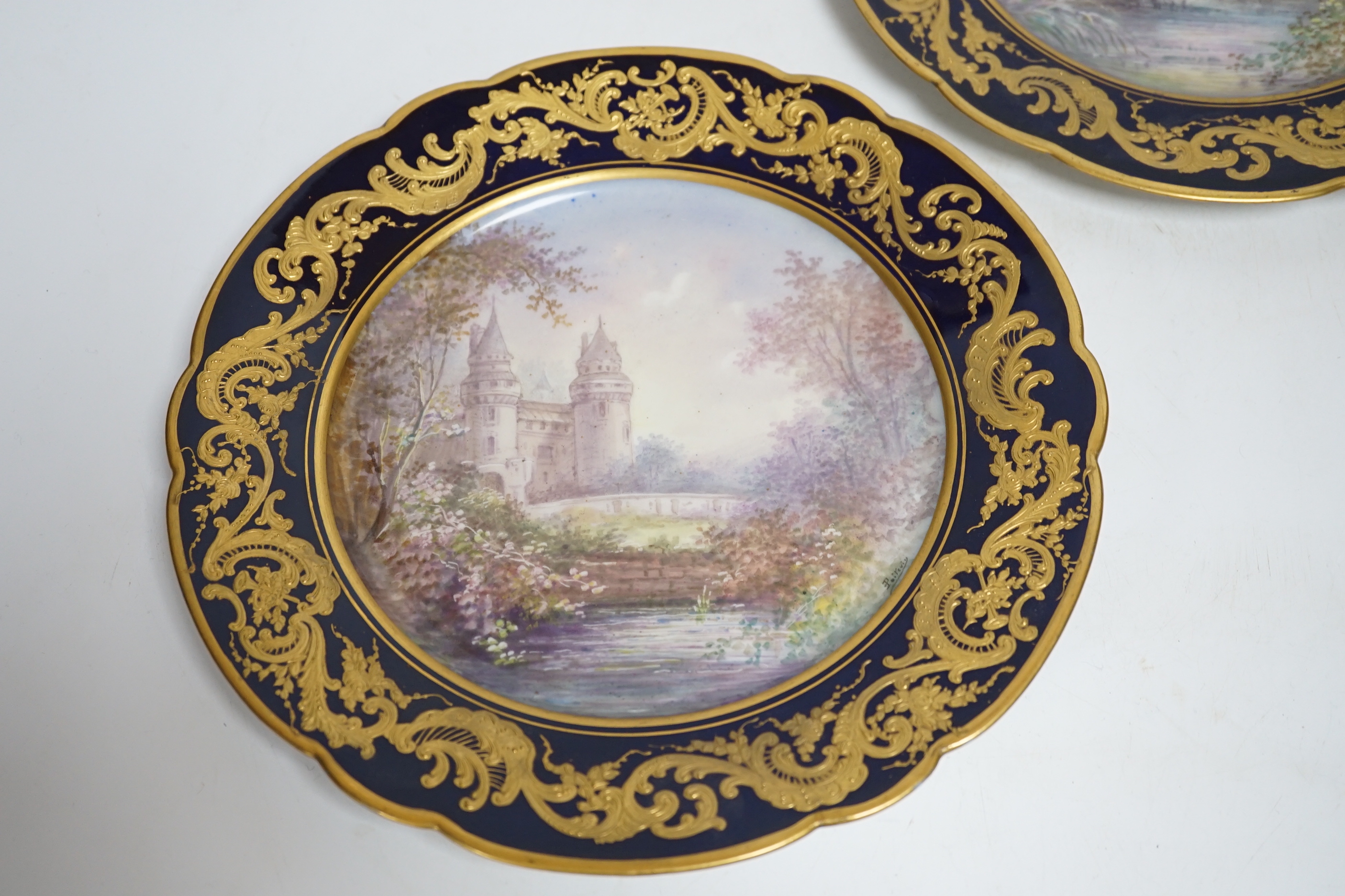 A pair of Sevres style blue cabinet plates, each decorated with a chateau, 24.5cm diameter